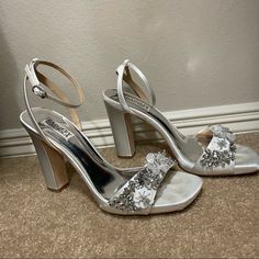 a pair of silver high heeled shoes sitting on the floor next to a wall