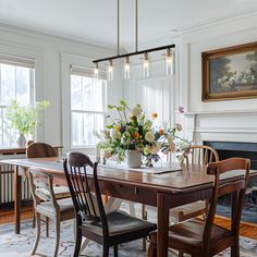 a dining room table with chairs and flowers on it