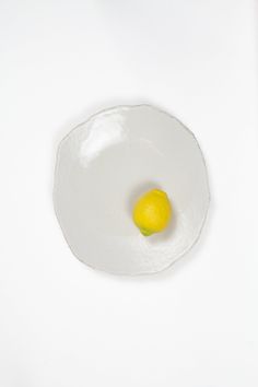 an egg in a white bowl with a lemon on the side, against a white background