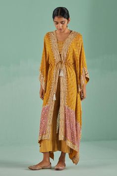 Ochre front open kaftan with chevron print and mirror, dabka work border. Paired with an inner geometric print blouse and trouser.
Components: 3
Pattern: Print, Embroidery
Type Of Work: Mirror, Dabka, Beads, Chevron
Neckline: Kaftan: V Neck
Sleeve Type: Kaftan: Three Quarter Sleeves
Fabric: Blouse and Trouser: Dull Bosky, Kaftan: Bamboo Georgette   
Color: Yellow
Other Details: 
Length: 
Kaftan: 46 inches
Blouse: 16 inches
Trouser: 38 inches
Occasion: Sangeet - Aza Fashions Open Kaftan, Mirror Blouse, Dabka Work, Yellow Mirror, Print Embroidery, Yellow Blouse, Chevron Print, Print Blouse, Three Quarter Sleeves