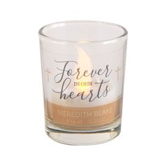 a candle holder with the words forever in our hearts written on it and a lit candle