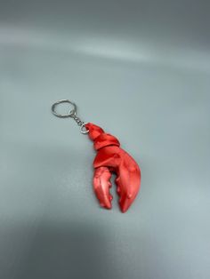 a red plastic animal shaped keychain on a gray surface with a metal hook