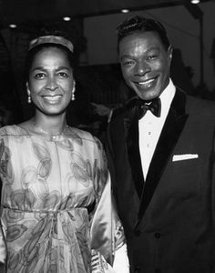 a man in a tuxedo standing next to a woman wearing a dress and bow tie