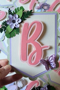 someone is holding up a card with the letter b on it and butterflies around it