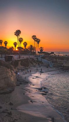 the sun is setting at the beach with palm trees