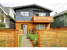 a house with a wooden fence in front of it and some plants on the side