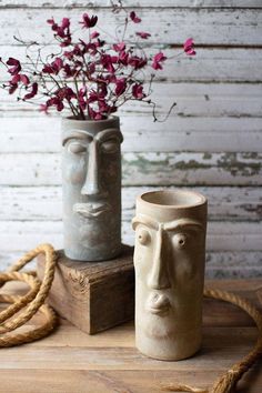 two vases with flowers in them sitting on a wooden table next to a rope