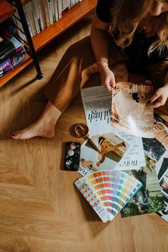 a woman is sitting on the floor with her legs crossed and assorted magazines in front of her