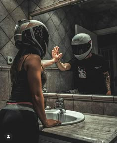 a woman in a helmet is washing her hands with another person standing at the sink