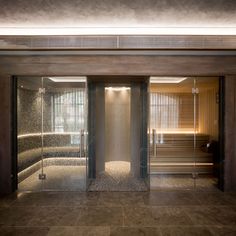 an indoor sauna with glass doors and stone flooring