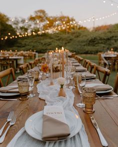 a long table with place settings and candles on it is set for an outdoor dinner