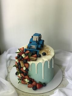 a cake decorated with berries, strawberries and blue truck