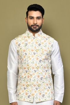 Beige sleeveless bundi with floral print and stitchline thread sequin embroidery and mandarin collared neckline. Paired with white full sleeve kurta and pant. - Aza Fashions Fitted Nehru Jacket With Zari Work For Spring, Sleeveless Nehru Jacket For Spring Wedding, Sleeveless Nehru Jacket For Diwali, Embroidered Sleeveless Nehru Jacket For Spring, Fitted Festive Vest For Spring, Sleeveless Bandhgala For Eid, Sleeveless Nehru Jacket With Floral Embroidery For Weddings, Fitted Sleeveless Nehru Jacket For Transitional Seasons, Sleeveless Embroidered Nehru Jacket For Diwali