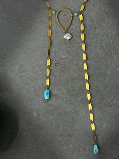 Capture the impactful symbology of natural gemstones with this artisan sequin bolo necklace. Adorned with a single natural keshi pearl, genuine Arizona Sleeping Beauty turquoise, micro faceted amazonite round & a hammered teardrop, this intentional necklace reflects the symbolism found throughout life's journey. Embrace the essence of the Desert & the Sea with peace of mind knowing this necklace was handcrafted in the USA with ethically sourced gemstones that tell a unique story. Baroque Keshi Pearl Sequin Chain Bolo Necklace Ft. Genuine Arizona Sleeping Beauty Turquoise (Necklace Only): ✿ Raw USA brass, natural baroque freshwater keshi pearl, genuine Arizona Sleeping Beauty turquoise, micro faceted Peruvian amazonite Please note - Items are made with raw bronze, copper & brass which may o Artisan Gold Jewelry With Pearl Charm, Bohemian Pendant Necklace With Pearl Charm, Gold Pearl Necklace With Spiritual Gemstone, Spiritual Gold Pearl Necklace With Gemstone, Artisan Pearl Charm For Jewelry Making, Adjustable Gold Turquoise Gemstone Necklace, Adjustable Gold Turquoise Necklace With Gemstone, Bohemian Silver Jewelry With Pearl Charm, Pearl Charm Pendant Jewelry In Brass