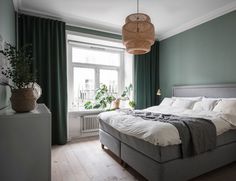 a bedroom with green walls, white bedding and wooden floors is pictured in this image