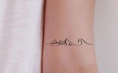 a woman's arm with a mountain tattoo on the left side of her wrist