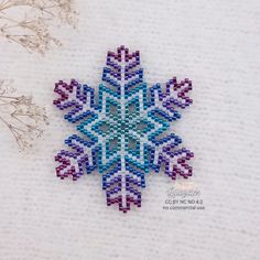 a beaded snowflake is shown on a white surface