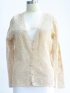 a white mannequin wearing a cream colored cardigan with crocheted details