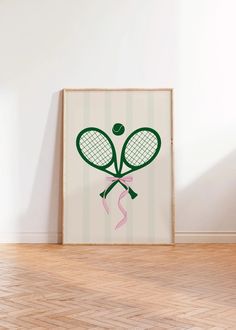 a tennis racket with a pink ribbon hanging from it's side in front of a white wall