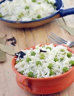 two bowls filled with rice and peas on top of a wooden table