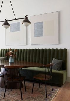 a green couch and table in a room with two pictures on the wall behind it