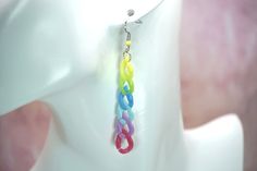 a pair of multicolored earrings hanging from a mannequin's head