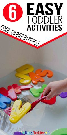 a child cutting out letters with scissors on top of an ice cream tub filled with water