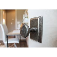 a door handle on the side of a white door with a dining room table in the background