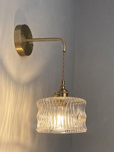 a wall light with a glass shade hanging from it's side on the wall