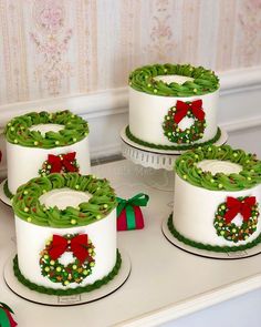 three decorated cakes sitting on top of a counter next to each other with bows and wreaths