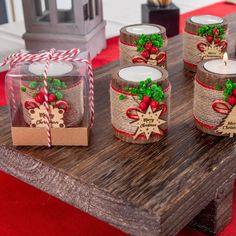 some candles are sitting on a table with red and green ribbons around them, wrapped in burlap