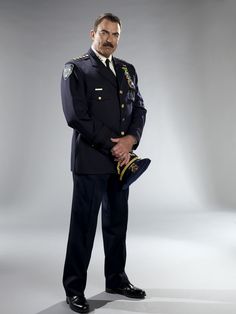 a man in uniform is standing with his hands on his hips and looking at the camera