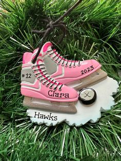 a pink ornament hanging from a christmas tree with two pairs of shoes on it