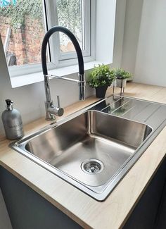 a stainless steel kitchen sink with faucet and soap dispenser next to it