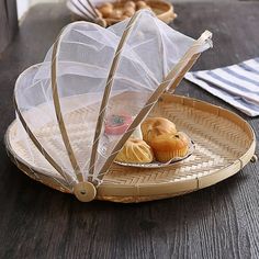 a basket with some food on it and an umbrella over the tray that is holding two muffins