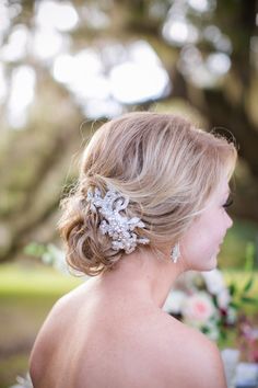 a woman in a wedding dress looking off into the distance with flowers on her head