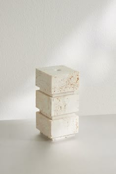 three white blocks stacked on top of each other in front of a white wall and floor