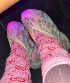 a pair of pink shoes sitting on top of a black floor next to a purple object