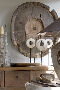 a table topped with lots of different types of candles next to a wall mounted clock