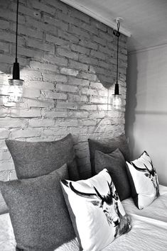 black and white photograph of pillows on a bed with brick wall in the back ground