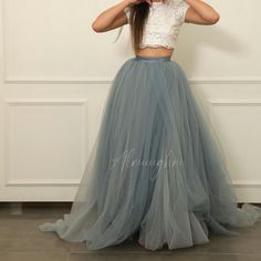 a woman wearing a gray tulle skirt and crop top with her hands on her head