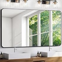 a bathroom with two sinks and a large mirror on the wall above it that is reflecting trees outside