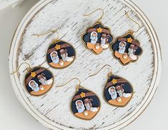 Celebrate the spirit of Christmas with these beautifully handcrafted polymer clay nativity scene earrings. Each pair features an intricate depiction of the Holy Family - Mary, Joseph, and baby Jesus - set under the Star of Bethlehem. These lightweight earrings are lovingly made with attention to detail, highlighting the warmth and meaning of the season. The soft colors of blue, brown, and white create a serene and festive feel, while the gold-tone hooks and accents add a touch of elegance. Perfect for holiday outfits, gifting, or as a special keepsake for the season, these unique nativity earrings will surely be a conversation starter. As each pair is handmade, slight variations may occur, adding to their unique charm. Please handle with care to preserve their delicate features. Each pair Nativity Earrings, Polymer Clay Nativity, Clay Nativity Scene, Scene Earrings, Clay Nativity, Jesus In Manger, Handmade Nativity, Mary Joseph And Baby Jesus, The Star Of Bethlehem