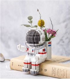 a flower pot made out of legos is sitting on top of a book with flowers in it