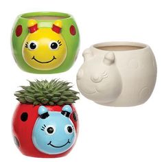 three ceramic pots with faces and plants in them