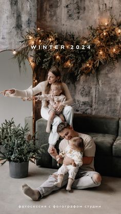 a family sitting on a couch in front of a christmas tree with lights and garlands