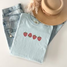 Welcome the sunny days with our delightful Summer Strawberry Embroidered T-Shirt! Made from 100% cotton, this t-shirt is not only comfortable but also perfect for staying cool during warm weather. Available in sizes S to 2XL and nine vibrant colors including Banana, Bay, Blossom, Butter, Chalky Mint, Chambray, Ivory, Orchid, and Peachy, there's a shade to suit every style.The standout feature of this t-shirt is the charming summer fruit-inspired design, showcasing four intricately embroidered strawberries on the center chest. Whether you're heading to a picnic, beach outing, or simply enjoying a leisurely day, this t-shirt adds a touch of sweetness to your summer wardrobe.Please note that colors may vary slightly due to monitor settings. For accurate sizing, refer to the size charts provid Casual Summer T-shirt With Embroidered Graphics, Cute Spring Tops In Organic Cotton, Cute Organic Cotton T-shirt For Everyday, Summer Cotton Top With Embroidered Graphics, Trendy Embroidered Summer T-shirt, Trendy Summer T-shirt With Embroidered Text, Trendy T-shirt With Embroidered Text For Summer, Summer Relaxed Fit T-shirt With Embroidered Text, Trendy Embroidered T-shirt For Summer