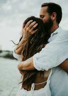 a man and woman embracing each other on the beach