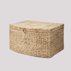 an empty wicker box with handles on the lid is shown in front of a gray background