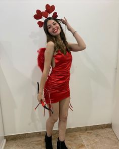 a woman in a red dress with hearts on her head, holding scissors and posing for the camera